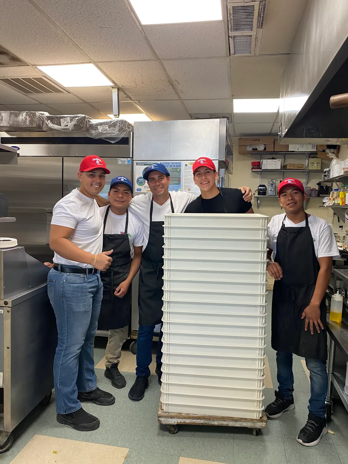 The Moravela’s crew in the kitchen with a tall stack of pizza boxes